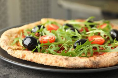 Zeytinli lezzetli pizza, kiraz domatesli ve roka kapalı bir masada, yakın plan.