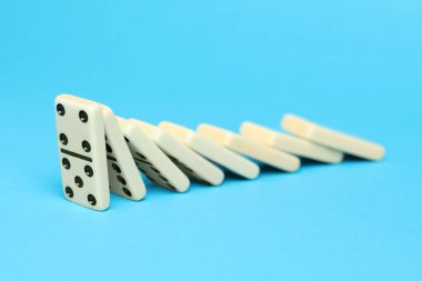 Domino etkisi. Kiremitler açık mavi arkaplana düşüyor