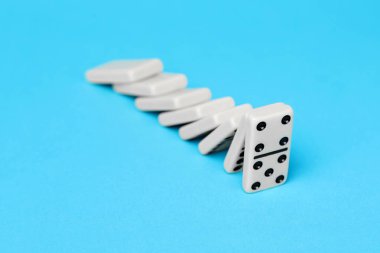 Domino etkisi. Kiremitler açık mavi arkaplana düşüyor