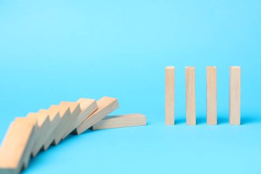 Domino etkisi. Açık mavi arkaplana düşen tahta bloklar