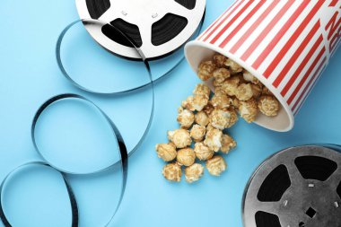Tatlı patlamış mısır ve film makaraları açık mavi arka planda, düz uzanmış