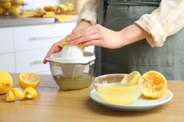 Tahta masada limonlu kadın meyve sıkacağı kullanıyor, yakın plan.