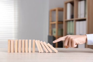 Domino etkisi. Masada tahta blokları iten adam, yakın plan.