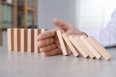 Ahşap blokların masada düşmesini engelleyen adam, yakın plan. Domino etkisi