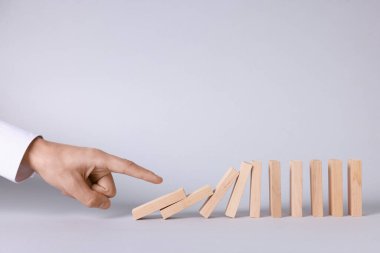 Domino etkisi. Adam arka planda tahta blokları itiyor, yakın plan