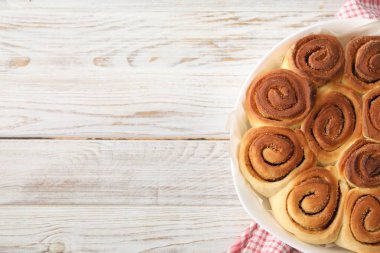 Hafif ahşap masada taze pişmiş tarçınlı rulo, üst manzara. Metin için boşluk