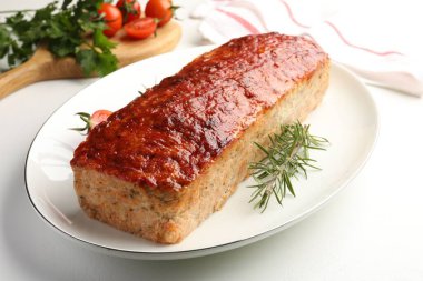 Lezzetli fırında hindi köftesi, biberiye, kiraz domatesleri ve maydanoz beyaz masada, yakın plan.