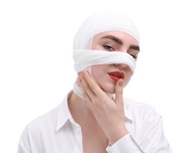 Beyaz arka plandaki estetik ameliyattan sonra burnu tıbbi bandaja sarılı bir kadın.