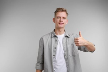 Mutlu adam gri arka planda, mesaj için boşluk gösteriyor. Jest gibi