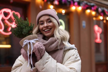 Açık hava dükkanının yanında thuja ağacı olan mutlu bir kadın. Mesaj için yer var. Noel sezonu