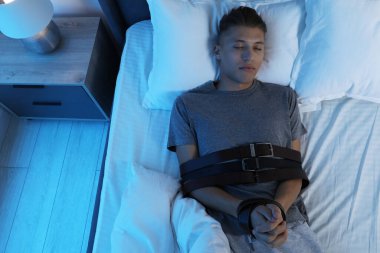 Uyurgezer kemerlerle bağlanır, yatağa uzanır.