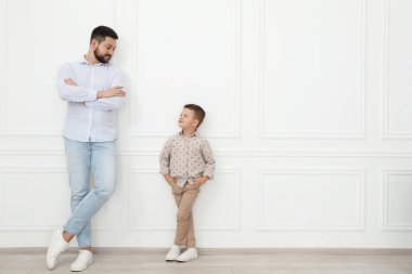Babası ve küçük tatlı oğlu beyaz duvarın yanında, mesaj için yer var.