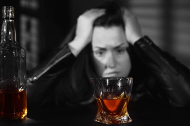 Alkol bağımlılığı. Masadaki depresyondaki kadın, bir bardak viskiye odaklan.