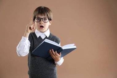 Alfabeyi öğreniyorum. Kahverengi arka plan kitabı olan küçük çocuk, mesaj için boşluk