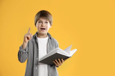 Alfabeyi öğreniyorum. Turuncu arka plan kitabı olan küçük çocuk, mesaj için boşluk