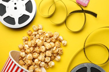 Tatlı patlamış mısır ve film makaraları sarı arka planda, düz yerde