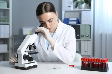 Laboratuvar testi. Doktor, mikroskopla kapalı bir masada çalışıyor.