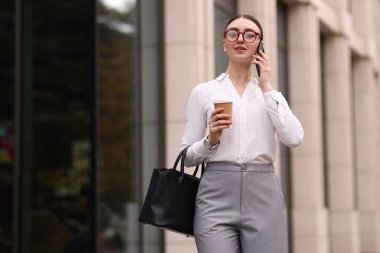 Şık giyinmiş bir kadın dışarıda telefonla konuşuyor. Metin için boşluk