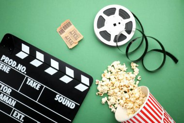 Film alkışı, lezzetli patlamış mısır, biletler ve yeşil arka planda film makarası, düz konum