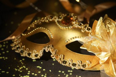 Güzel bir karnaval maskesi, koyu arkaplanda kurdele ve konfeti, yakın plan.