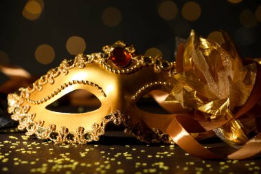 Güzel bir karnaval maskesi ve koyu arkaplanda bulanık ışıkları olan konfeti, yakın plan.