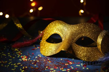 Güzel bir karnaval maskesi ve koyu arkaplanda bulanık ışıkları olan konfeti, yakın plan.