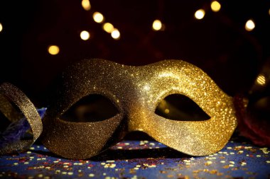 Güzel bir karnaval maskesi ve koyu arkaplanda bulanık ışıkları olan konfeti, yakın plan.