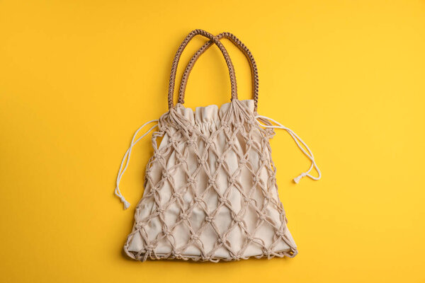 Macrame shopping bag on yellow background, top view