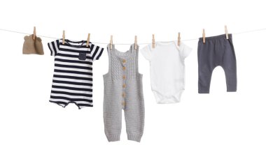 Different baby clothes drying on laundry line against white background