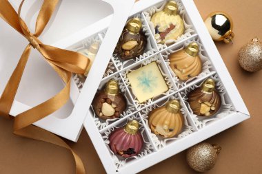 Açık kutuda süs eşyası şeklinde lezzetli çikolata ve bej arka planda Noel süsü.