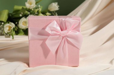 Güzel düğün hediyesi, ipek kumaş ve çiçekler masada.