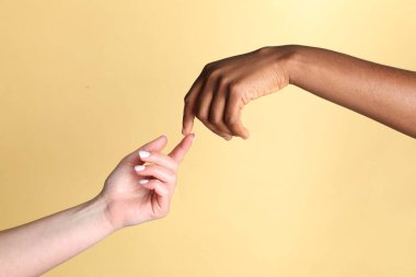 Irkçılığı bırak. Bej arka planda el ele tutuşan farklı ten renklerinden insanlar, yakın plan