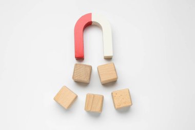 Beyaz arka planda tahta küpleri çeken mıknatıs düz yatıyordu.