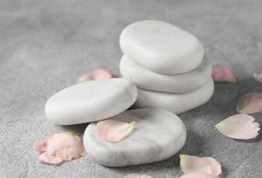 Gri masadaki kaplıca taşları ve taç yaprakları, yakın plan.