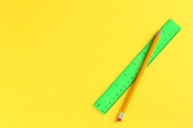 Sarı arka planda cetvel ve kalem, üst manzara. Metin için boşluk
