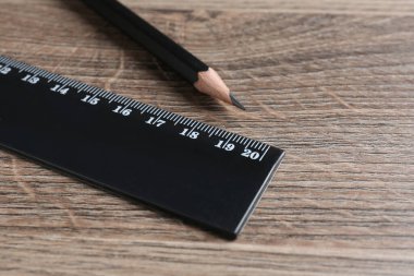 Siyah cetvel ve kalem ahşap masada, yakın plan.