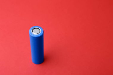 Kırmızı arka planda bir tane AA cep telefonu pili, yakın plan. Metin için boşluk