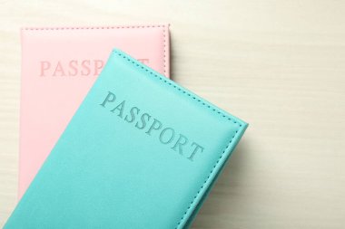 Beyaz ahşap masa üzerinde parlak örtülü iki pasaport, üst manzara. Metin için boşluk