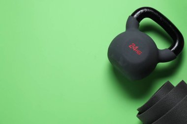 Yeşil arka planda kettlebell ve mat, üst manzara. Metin için boşluk