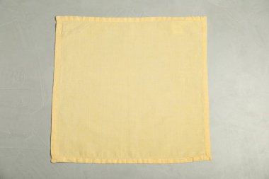 Açık gri masada açık sarı peçete, üst manzara.