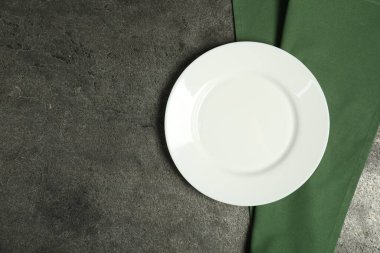 Yeşil peçete ve gri masadaki boş tabak, üst manzara. Metin için boşluk