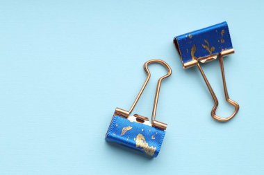 Açık mavi arka planda iki cilt klipsi, düz. Metin için boşluk