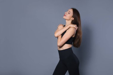 Gri arka planda şık spor kıyafetleri içinde güzel bir kadın. Metin için boşluk