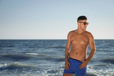 Kumsalda çekici vücutlu yakışıklı bir adam. Metin için boşluk