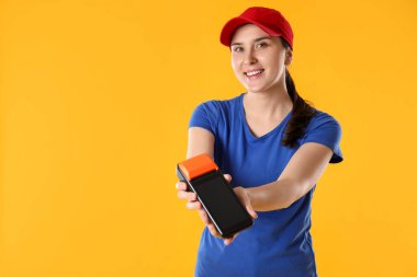 Sarı arkaplanda ödeme terminali olan mutlu kurye, metin için boşluk