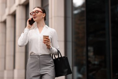 Şık giyinmiş bir kadın dışarıda telefonla konuşuyor. Metin için boşluk