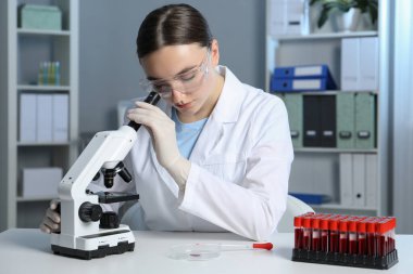 Laboratuvar testi. Doktor, mikroskopla kapalı bir masada çalışıyor.