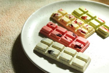 Açık dokulu masa üzerinde farklı aromalı lezzetli çikolatalar, yakın plan.