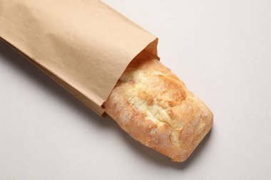 Açık gri masa üzerinde taze ekmek torbası, üst manzara.