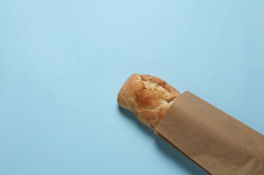 Açık mavi arka planda taze baget ve kağıt torba, üst manzara. Metin için boşluk